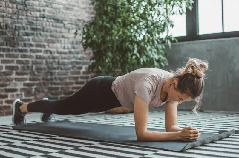 Hướng dẫn đặt cùi chỏ vuông góc 90 độ ngay dưới vai khi bắt đầu bài tập plank.